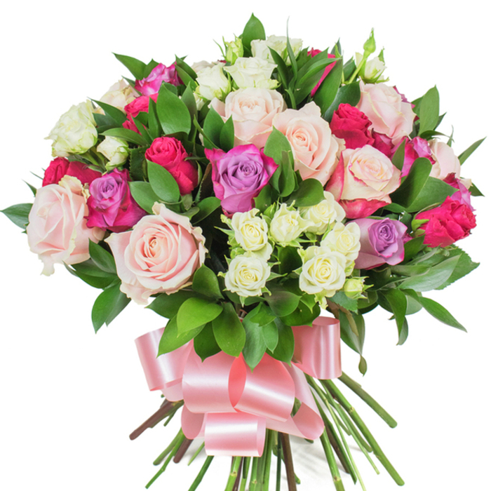 This hand-composed, rounded bouquet of mixed roses is set against a stark white background, allowing each colour and texture to read clearly. The arrangement centres on full-bodied roses in soft pastel pink and creamy white, many unfurled to reveal delicate petal structure and subtle shading; a selection of hot fuchsia roses introduces vivid contrast while a few lavender-toned roses lend a cool, gentle accent. Throughout the massed blooms sit tidy clusters of spray roses-smaller, cream-coloured flowers with pale yellow hints-that add fine-scale texture and help the eye move across the composition. Interspersed foliage of dark green, glossy ruscus or salal forms a verdant skeleton, its elongated leaves placed to support and lift the heads of the roses while amplifying their colour saturation. The stems are gathered and bound at the base, finished with a wide, lustrous baby-pink satin ribbon tied into an elegant bow whose loops and tails catch light and introduce a soft sheen beneath the flowers. The white backdrop highlights the tactile qualities-the velvet of the petals, the crispness of the leaves, and the neatness of the tied stems-and suggests a soft, natural scent: classic rose notes with a fresh, green undertone. Made with the sensibility of a local florist working near Golders Green Tube and the shops on Golders Green Road, this bouquet conveys celebration, affection, and refined charm suitable for birthdays, anniversaries, or a thoughtful Mother's Day expression.