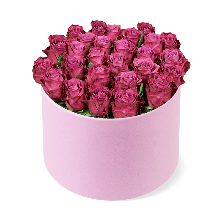In this image, a luxurious rose hat box arrangement is showcased like a modern sculpture, standing alone against a pure white background that highlights every detail. The container is a round, light pastel pink cylinder, with a subtle matte, almost suede-like texture that feels refined and contemporary, as if sourced from an upscale gift shop just off Golders Green Road. From its open top emerges a tightly composed dome of roses in deep fuchsia and rich magenta shades, each bloom nestled so closely that they form a soft, cushion-like surface of petals. The roses are at various stages of early bloom, some still cupped and compact, others beginning to unfurl, revealing spirals of petals that transition from softer, rosy pink in their centres to more vivid, berry-infused tones at the edges. The effect is a rich, jewel-toned canopy that completely obscures the inside of the box. Here and there, tiny glimpses of dark green foliage peek out, adding just a touch of contrast without disturbing the opulent mass of colour. The smooth line of the hat box's rim and its gently curved sides draw the eye upward toward the lush crown of roses. Illuminated by soft, even light, the arrangement casts a faint shadow, giving a sense of three-dimensional presence, like a gift placed carefully on a dining table in a Golders Green townhouse before guests arrive. The mood is romantic yet polished, capturing the essence of a premium floral gift perfect for anniversaries, Valentine's Day surprises, or celebrations that call for something both dramatic and undeniably elegant in NW11.