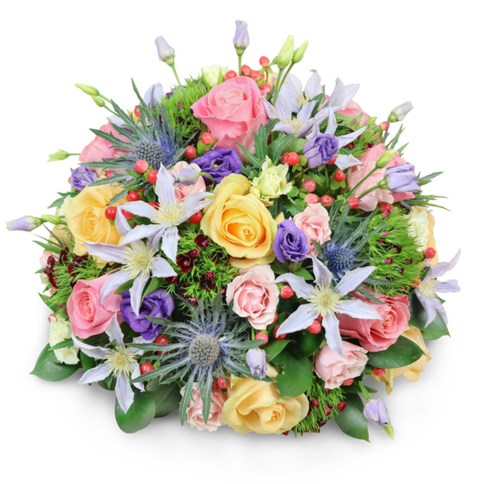 A meticulously constructed dome of blooms is photographed against pure white, its rounded volume emphasized by a soft shadow that suggests careful studio styling. Prominent throughout are garden roses in soft pink, creamy peach, and warm yellow, presented in a range of opening stages so some show tightly furled centers while others reveal full, swirling layers. Interspersed are clematis blossoms in pale violet and near-white, their star-like petals and warm yellow cores offering delicate focal points among the roses. Blue Eryngium, with their spiky, maritime-blue heads and textured bracts, introduce a striking, sculptural contrast that lifts the palette away from strictly traditional. Deeper purple lisianthus add velvety accents and a play of form, while clusters of bright red Hypericum berries provide lively punctuation and a glossy contrast to the soft petals. The green infrastructure of the bouquet is rich and varied: broad, glossy leaves form a strong foundation, finer ferny greens create dimensional softness, and hints of nearly burgundy foliage give shadowed depth and complexity. Light skims the surfaces, creating subtle highlights that enhance the impression of freshness; one can almost sense a soft floral fragrance with a gentle green note. Hand-crafted for visual impact and balance, this arrangement reads as both celebratory and composed - suitable for centrepieces, thoughtful gifts, or expressions of sympathy conveyed with quiet elegance. Prepared with local knowledge and care by Flowers Golders Green to reflect the refined tastes of the area, it nods to nearby green spaces and the floral sensibility of Golders Green shoppers seeking fresh, textural bouquets.