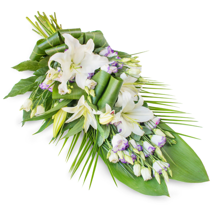 A classic teardrop-shaped funeral spray is laid out against a bright white background, capturing every nuance of its elegant, flowing form. The arrangement begins as a generous cluster at the upper left, where the stems are bound together, then narrows gradually toward a fine, pointed tip at the lower right, echoing both a falling leaf and a gentle farewell. At the centre are several imposing white oriental lilies, their large, waxy petals unfurling in layers, revealing soft green throats and subtle stamens that add a hint of golden warmth to the otherwise cool palette. Some lilies remain in bud, standing tall and tapered, conveying a quiet message of hope and continuity. Around them, groups of lisianthus blooms add delicacy; their white petals, brushed at the edges with lavender and traced with fine purple lines, bring a muted touch of colour reminiscent of evening light over nearby Golders Green Crematorium gardens. Numerous closed and half-open lisianthus buds contribute texture and rhythm, punctuating the design. Surrounding all of this, lush greenery gives both support and contrast: broad, deep green leaves provide a verdant backdrop, while a selection of leaves is carefully folded and rolled into sculptural elements near the centre, adding modern flair to a traditional tribute. From the right, slender palm-style fronds fan out gracefully, reinforcing the elongated shape and suggesting a gentle, outward-reaching gesture of love. The overall impression is one of composed, solemn beauty, the kind of dignified sympathy arrangement that families around Golders Green might choose to honour a loved one at a chapel, cemetery, or quiet home gathering.
