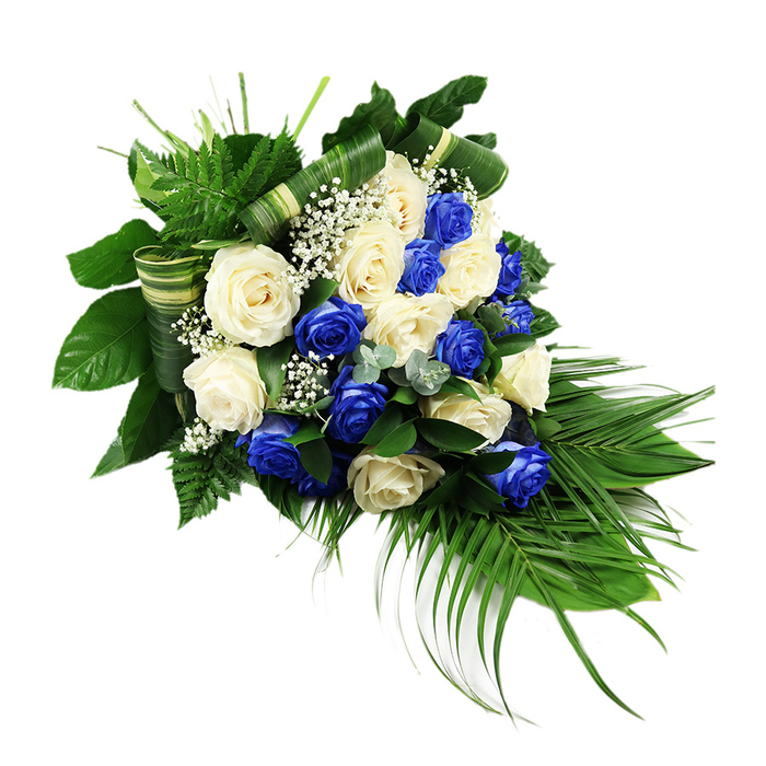 A sophisticated, elongated floral spray of blue and white roses is presented against a clean white background, its carefully composed shape evoking a falling teardrop or a gentle crescent of blooms. The focal point is a dense cluster of roses, each flower fully opened so the layered petals appear almost sculptural. Creamy ivory roses mingle with pure white ones, their soft tones bringing a sense of purity, while equally numerous deep sapphire blue roses thread through the arrangement, creating striking islands of colour. The blue roses are rich and saturated, reminiscent of evening skies over nearby Golders Hill Park, and they lend the display a feeling of quiet strength and loyalty. Tiny sprays of white baby's breath are woven throughout, their delicate, star-like blossoms adding fine texture and a touch of airiness between the larger blooms. Encircling the roses, an abundance of greenery gives the spray structure and flow. Broad, dark green leaves form a strong, supportive base at the upper left, while lighter, feathery ferns rise above the roses, adding height and softness. Long palm fronds extend from the base of the arrangement, reaching downwards and outwards in tapering lines that define the cascading silhouette. Here and there, soft bluish-green eucalyptus-style sprigs break up the darker foliage, introducing a cool, silvery note. Some of the wider leaves are expertly folded and wrapped into horizontal bands, creating refined stripes of green and cream that run across the design and hint at the florist's precision and craftsmanship. The overall composition feels serene and reverent, an elegant sympathy spray one might send from Flowers Golders Green to accompany a funeral, memorial, or graveside service in the local area, offering a visual message of peace, remembrance, and steadfast love.