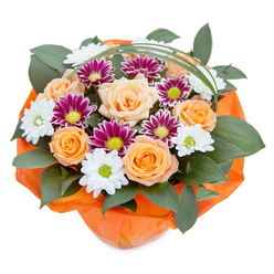 Bursting with the joyous energy found in the heart of Golders Green, this bouquet is a true celebration of colour and texture. Carefully arranged on a crisp white backdrop, the bouquet's center showcases spiralled roses glowing from velvety peach to radiant tangerine, their warmth reminiscent of a sunlit stroll along Golders Green Road. Clusters of chrysanthemums add intrigue: the white daisy-like ones radiate freshness with pristine petals and bright green eyes, evoking local gardens in full bloom; the deep magenta variants lend rich contrast, their lime-green centers sparkling like gems. Threads of glossy dark green foliage envelop the flowers, providing both a sense of abundance and the kind of lush, layered depth seen in the natural spaces surrounding Hampstead Garden Suburb. Elegantly arching over the top, a slender ribbon of decorative grass gives the display a modern flair, as if windblown from nearby parks. The base, tightly gathered in crinkled orange cellophane, wraps the composition in warmth and anticipation, perfect for occasions ranging from family milestones to neighbourly gestures of kindness. Whether gracing a local home or delivered anywhere across the NW11 area, this bouquet's lively palette and expert arrangement tell a story of community, celebration, and uplift-an invitation to pause and savour the beauty flourishing within Golders Green.