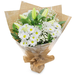 A carefully composed bouquet that celebrates the purity of white with a modest, uplifting spirit - a bouquet we might craft at Flowers Golders Green behind the shop on Golders Green Road, with neighbourhood deliveries to Temple Fortune and around Golders Hill Park. The arrangement centres on abundant white chrysanthemum heads, each formed by layers of slender petals fanning from a sunlit yellow eye, creating a cheerful yet refined core. Threaded among them are several long, pale green-yellow lily buds, some with faint striping, holding back their blooms to add elegant anticipation and vertical interest. Tiny clusters of baby's breath (Gypsophila) are woven through the arrangement, their miniature white flowers forming soft, cloud-like pockets that lift the composition and introduce a delicate, airy texture. Rich, dark green foliage provides depth and contrast, framing the flowers and emphasising the crispness of the whites under soft studio light. The stems are hand-gathered and wrapped first in a rustic, crinkled brown kraft paper that gives an earthy, tactile feel, then protected with a glossy clear cellophane sleeve which both preserves and displays the bouquet. The wrapping is neatly gathered and tied at the base to create a stable, easy-to-carry presentation. The overall impression is one of tranquil refinement - a bouquet that smells faintly of fresh leaves and clean florals - fitting for occasions such as new births, quiet anniversaries, get-well wishes, or moments of remembrance across Golders Green and nearby Finchley Road.