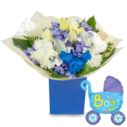 A tender, celebratory bouquet arranged to announce a baby boy, presented with a playful carriage-shaped balloon that reads It's a Boy. The flowers are gathered into a compact, rounded design and placed in a solid royal-blue gift box that gives the composition a modern, grounded silhouette. Creamy white roses and long, elegant white lilies-some with buds still closed-provide a serene, fragrant core, while plush white spray chrysanthemums add a soft, textural backdrop. Vivid electric-blue chrysanthemums and a striking cluster of deep blue blooms create a vibrant counterpoint, their saturated petals bringing joyful energy. Interspersed among them are clusters of soft lavender or periwinkle blossoms, similar to small hyacinths, which add a powdery perfume and fine detail. Lush greenery, from broad glossy leaves to delicate fern-like fronds, nestles between stems and lifts the arrangement visually from the cream-coloured tissue wrapping gathered neatly at the base. To the right, a pale-blue foil pram balloon floats with darker-blue trim, dotted wheels and tiny heart motifs; the cheerful yellow-green lettering spells out the announcement. The light is soft and natural, catching the shimmer of the balloon and the dewy surface of petals, so the whole set feels intimate and celebratory. Prepared with the care of a Golders Green florist, this bouquet and balloon pair is ideal for hospital doorsteps, baby showers near Hampstead Garden Suburb, or a warm welcome home delivery across the local streets.