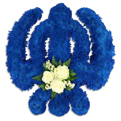 A striking Sikh Khanda funeral tribute dominates the frame, crafted entirely from deep royal blue flowers and set against a crisp white background so that every sacred curve stands clear and unapologetically bold. The familiar outline of the central khanda sword, encircled by the chakkar and flanked by two crossed kirpans, is shaped from densely clustered blue chrysanthemum heads, each ruffled petal catching light and shadow to give the emblem a richly textured, almost velvet-like appearance. This sea of blue feels contemplative and solemn, like a quiet evening walk through Golders Green after a service at the gurdwara. At the lower centre of the sword, a gentle counterpoint appears in the form of a small, carefully placed posy. Three white roses, perfectly formed and just beginning to open, sit side by side, surrounded by tiny white filler flowers and sprigs of polished green foliage. The white blooms seem to glow against the blue, a symbol of purity, remembrance, and the soul's journey, while the foliage adds a living, breathing green freshness, as if recently arranged by skilled hands in a local Golders Green flower shop. Soft shadows around the emblem emphasise its solid, three-dimensional presence, suggesting a substantial tribute resting on a stand at a Sikh funeral, memorial, or celebration of life. The design speaks of devotion to Sikh identity and tradition, conveying sympathy and respect to families in Golders Green who wish to honour their loved one with a culturally meaningful floral arrangement.