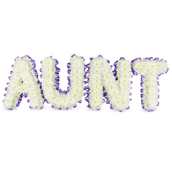 This personalised memorial piece spells 'AUNT' in bold, elegant capitals, each letter densely composed of hundreds of small white spray chrysanthemums whose tight, papery petals create a plush, cloudlike surface. The flowers' pale yellow centres show through in places, lending a gentle, sunlit warmth beneath the predominantly white blooms. Encircling every letter is a rich purple satin ribbon, pleated and slightly ruffled to add texture and a refined finishing line that contrasts softly with the flowers' matte petals. Soft, neutral shadows beneath the letters make them read as freestanding forms, giving the tribute a three-dimensional presence suitable for laying against a chapel lectern or standing beside a family photograph at a memorial. The scent is implied rather than overpowering-fresh, green, and almost dewy-complementing the visual calm. As a local florist with many commissions across Golders Green, near Golders Hill Park and Golders Green Road, we arrange these pieces to balance reverence with a celebration of life: the white chrysanthemums for remembrance, the purple ribbon for dignity and quiet respect. The overall feeling is one of steady compassion and handcrafted care-a noble, comforting farewell that holds personal memory and communal sympathy together in a single, composed gesture.