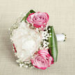 Captured against a subtly textured, off-white fabric that feels like fine linen, this hand-tied bouquet embodies understated bridal elegance with a distinctly North West London charm. The central focus is a single, sumptuous creamy white peony, its densely packed petals unfolding in layer upon layer, forming a soft, voluminous bloom that looks almost cloudlike in the gentle light. Framing this luxurious heart are two vivid pink roses, one placed just above and one just below the peony, their petals spiralling outward from tight centres into tones that deepen from blush to rich magenta along the outer edges, giving the bouquet a refined yet romantic burst of colour. Threads of white baby's breath weave between the larger flowers, their tiny, starry blossoms creating an airy halo that softens every line and adds a feeling of lightness and celebration. Around the base, wide, glossy aspidistra leaves curve gracefully, encasing the stems in a sleek green cradle that provides structure and a strong contrast to the soft pastels above. The stems themselves are meticulously wrapped in smooth white satin ribbon, clearly designed to be comfortably held for a wedding ceremony at a local Golders Green synagogue or a registry office near Hampstead. The overall composition, thoughtfully crafted in the style of an experienced neighbourhood florist, feels fresh, modern, and deeply romantic, perfect for wedding features, inspiration for brides planning photos around Golders Hill Park, or anyone searching for a sophisticated bouquet to mark a milestone moment in NW11.