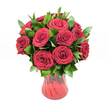 A lush, romantic bouquet of around a dozen deep red roses is gathered closely together in a classic, round arrangement, displayed in a translucent ruby-red glass vase against a clean white studio background. Each rose is fully open, with layers of velvety petals spiralling inward to a tight centre, creating that familiar, luxurious swirl associated with premium florist-quality blooms. The red is intense and even, leaning toward rich crimson rather than bright scarlet, giving the bouquet a sense of depth and passion that feels ideal for an anniversary or heartfelt declaration of love. Between the roses, generous sprigs of dark, glossy green foliage - likely ruscus or a similar leaf often used in Golders Green flower shops - weave in and out, breaking up the red and adding natural texture and fullness. The foliage has a waxy sheen, catching the soft, even lighting and subtly reflecting highlights, which makes the bouquet appear freshly arranged, as if it has just been prepared in a local studio near Golders Hill Park. The red glass vase has a gently curving silhouette that narrows toward the base, with a flared rim that supports the rounded dome of blooms. A faint ribbed or swirled texture in the glass catches the light, allowing deeper and lighter tones of red to appear where the glass thickens or thins. The crisp white background ensures every detail of the roses, leaves, and vase is clearly defined, giving the entire arrangement a modern, polished look. The image conveys warmth, romance, and sincerity, perfectly suited to represent a classic red rose gift delivered across Golders Green for occasions like Valentine's Day, proposals, or milestone celebrations.