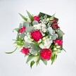Viewed from directly above against a flawless white background, this exuberant bouquet forms a full, rounded circle of colour, like a little celebration captured on a tabletop in Golders Green. At the heart of the design, large hot pink carnations unfurl in dense, frilled layers, their ruffled petals creating a rich, velvety texture that almost seems to move in the soft light. Nestled among them are deep pink and fuchsia roses, some fully open with classic spiral centres, others still in tight buds that hint at flowers yet to unfold, adding a feeling of anticipation and new beginnings. Scattered throughout, clusters of tiny white spray chrysanthemums and daisy-like blossoms form soft, clouded patches that brighten the arrangement and bring a sense of crisp freshness, like a cool breeze drifting through nearby Golders Hill Park. Airy sprigs of white gypsophila weave delicately between the larger blooms, their tiny blossoms floating above the design and giving it a light, romantic haze. Slender white buds, likely alstroemerias or lily-style flowers, rise gently from the mix, adding a quiet elegance and purity to the lively pinks. Around the blooms, a generous collar of greenery creates structure and depth: rounded, silvery-green eucalyptus leaves offer a cool, calming tone and smooth, almost waxy texture, while long, vivid green blades of foliage arc gracefully outward. Broader, darker leaves-expertly folded and layered-form a carefully constructed frame, cradling the flowers and making the colours appear even more intense. The overall impression is joyful and affectionate, a bouquet that feels perfect for sending congratulations, birthday wishes, or a heartfelt thinking of you to someone in Golders Green, whether they live off Finchley Road, near the station, or along a quiet residential lane.
