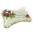 A pillow-shaped funeral cushion, photographed against a clean white background, composed of a dense, cloud-like bed of small, pristine white chrysanthemums whose tightly packed florets create a soft, plush texture that invites a quiet, tactile memory. Along the top-left corner a clustered bouquet of deep magenta to fuchsia roses opens with velvety petals, their rich colour set off by delicate sprays of white freesia and a few creamy lisianthus blooms that lend a gentle perfume and a fragile, lyrical note. Fresh green foliage-feathery fern fronds and smaller glossy leaves-frames the accent cluster and brings natural depth and contrast to the otherwise serene white surface. From that cluster, two or three slender, arching stems of bright green linear foliage, likely bear grass, sweep diagonally across the cushion, creating an elegant visual flow that draws the eye toward the opposite edge. A single magenta rose, carefully placed near the lower-right corner and cradled by its own tiny leaves, balances the composition and echoes the main grouping to create quiet symmetry. The entire perimeter is finished with a folded lime-green satin ribbon trim, a scalloped pleat that gives the pillow a soft framed edge and a discreet flash of colour. The lighting is gentle and even, the shadows soft, reinforcing the calm, respectful mood of the tribute. This arrangement reads as a timeless expression of condolence-peaceful, reverent, and crafted with the hands of an experienced florist-suitable for delivery to services at Golders Green Crematorium or a family home near Golders Hill Park.