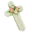A dignified, three-dimensional funeral cross crafted from hundreds of small, snowy white button chrysanthemums fills the frame against a clean white backdrop, the soft drop shadow lending the arrangement gentle depth. The tiny, tightly clustered florets form a plush, velvety surface across the classic Latin cross shape, their crisp white faces suggesting purity, peace and quiet reverence. At the crossing of the arms a careful cluster of open garden roses draws the eye - buttery ivory, soft blush pink and warm peach-apricot blooms arranged like a small garden bouquet. Slender green fern fronds weave between the roses, adding feathery texture and a natural curve, while delicate sprigs of pale lavender filler offer a whisper of cool colour and subtle contrast. Around the outer edge a neat band of lime-green ribbon peeks out beneath the white blossoms, giving a fresh, modern outline that lifts the composition without distracting from its solemn tone. The blooms appear freshly cut, the petals slightly dewy in imagined touch, the scent muted and comforting rather than overpowering. The overall impression is one of careful craftsmanship and respectful restraint, a traditional memorial piece suited to a church service, graveside tribute or wake. As a local florist I picture this arrangement arriving at Golders Green Crematorium on Hoop Lane or being placed with care near the family at a chapel on Golders Green Road - an understated expression of condolence that reads as both faith and farewell, designed to soothe and honour in moments of quiet remembrance.