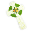 A three-dimensional Celtic cross crafted entirely from fresh flowers, seen from a slightly elevated angle against a crisp white backdrop that lets each bloom read clearly. The principal form is built of tightly clustered, pure white spray chrysanthemums whose small petals create a soft, plush surface and a dignified, almost cloud-like texture along the arms and elongated shaft. Interwoven through that white field are bright apple-green button chrysanthemums, their compact rounded heads arranged to outline the signature circular ring where the cross's arms meet and to fill alternating segments along the horizontal arms, lending a tactile, almost beaded contrast that catches the eye. At the very centre, where the arms intersect, three fully opened orange roses-warm, golden-amber in tone-form a small, luminous focal point; their layered petals bring an intimate, human warmth against the cool white and fresh green. Dark green fern fronds and delicate foliage frame that trio, sharpening the colour contrasts and adding a quiet depth and softness to the silhouette. The lighting is soft and clear, suggesting morning studio light that highlights petal texture and the cross's low-relief sculptural form, and a subtle floral scent of chrysanthemum and rose would likely linger in the air. This arrangement reads as a respectful sympathy or funeral tribute that honours Celtic symbolism and Irish heritage: the colour balance subtly echoes the Irish flag while the cross shape speaks to spiritual comfort and memory. As a local Golders Green florist might note, it's the kind of carefully composed memorial piece we assemble with attention to proportion and sentiment, ready to be placed at a funeral or laid on a grave with measured dignity.